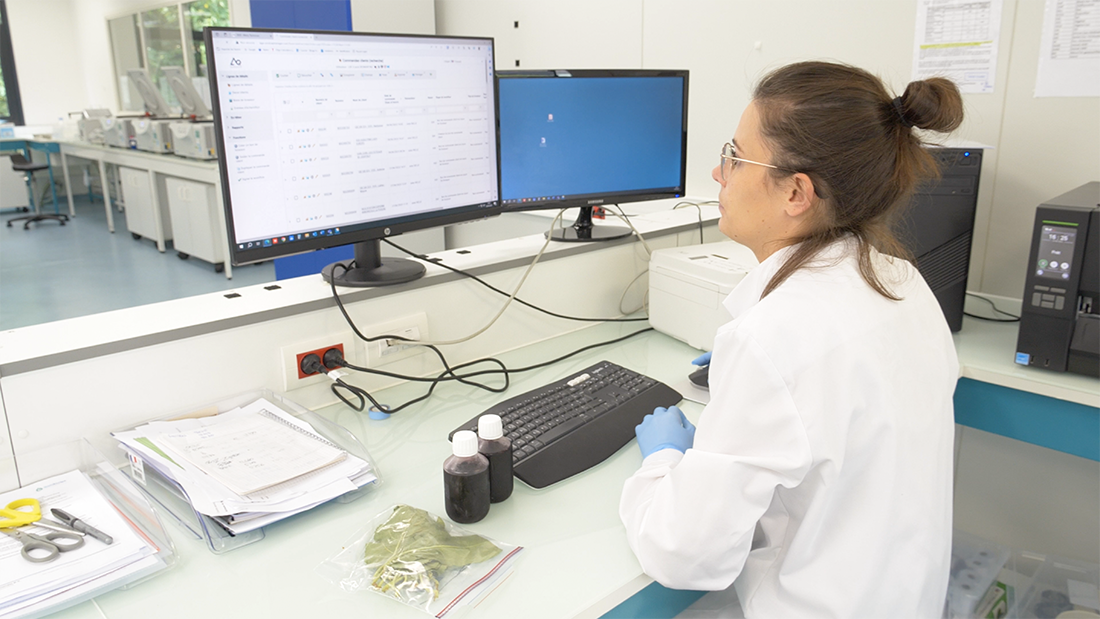 Technicienne de laboratoire consultant des résultats d'analyse sur deux écrans